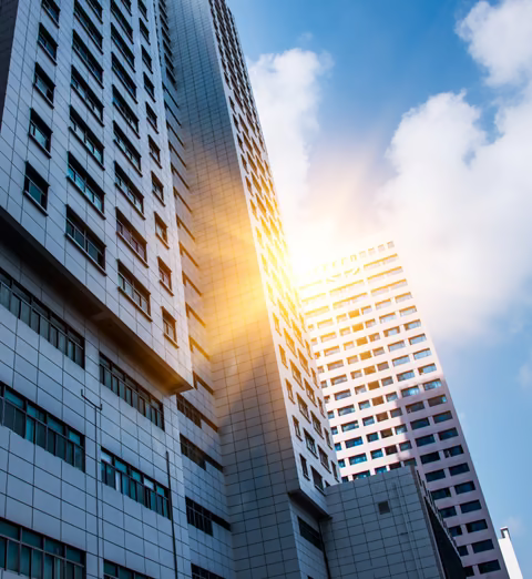 Commercial office towers seen from below with sunlight breaking through