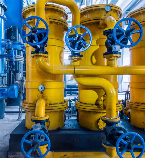 Yellow industrial pipes with blue valve wheels in a manufacturing plant